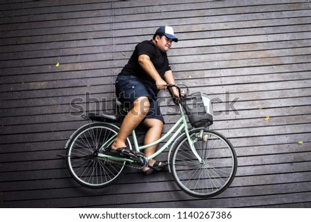 Create ideas for ride bicycle of fat man on wooden road, Holiday travel in thailand, Motivation to exercise.