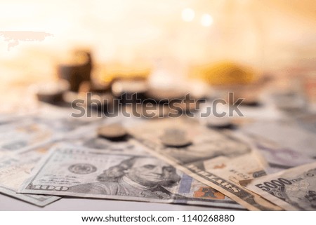 Various of international money coin and banknote with blurred hourglass in the background. Time investment with currency exchange concept. Focus on dollar banknote.