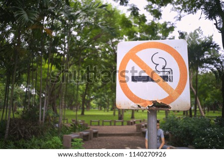 an old no smoking sign in a green park