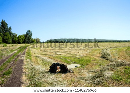 man's clothing and mown hay, lies on the field against the background of the sky and Cretaceous mountains.