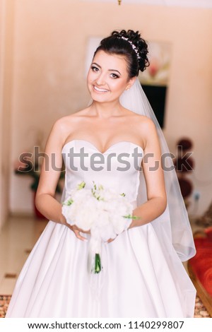 Portrait of the smiling bride holding the wedding bouquet of roses.