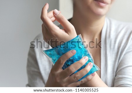 Wrist pain. The woman puts the gel pack to the hand. First aid.                           Royalty-Free Stock Photo #1140305525