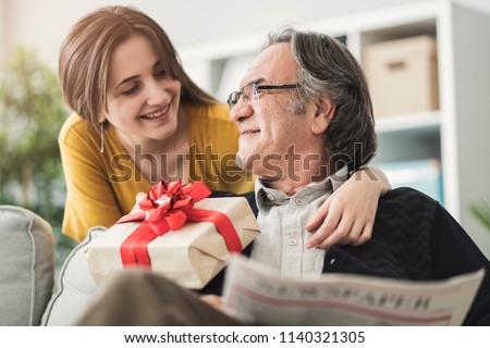Young woman giving gift her father