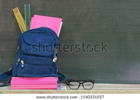 Back to school concept.Books, textbooks, backpack and stationery supplies on blackboard.