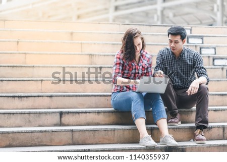 Two College young students sitting using laptop and discussing meeting ideas for project and working at Staircase university. Education Knowledge Concept