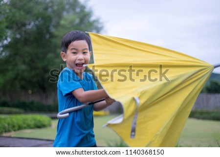 Cute little boy standing and fun yellow umbrella with outdoor background