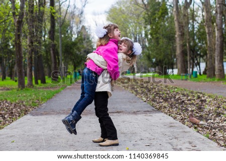 Two funny siblings sister hugging with each other while walk in park. Having fun together, positive emotions, bright colors. Copy space. Back to school