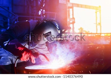 Mig welder man working process success with steel pipe on sparks light wear protective equipment and mask isolated on dark tone background Royalty-Free Stock Photo #1140376490