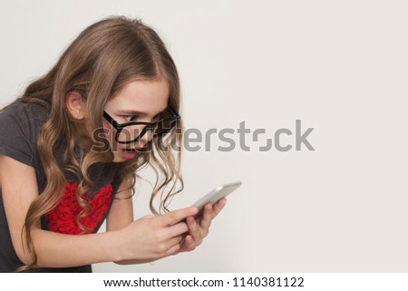 Amazing news. Shocked little girl looking at mobile phone screen on white background, copy space