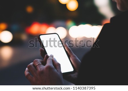 Cropped view of young woman holding smartphone with blank screen area for your internet content on bokeh background.Female finger typing text on website on digital mobile phone using 4G connection