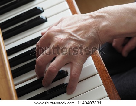 Elderly female hands playing the piano, close up