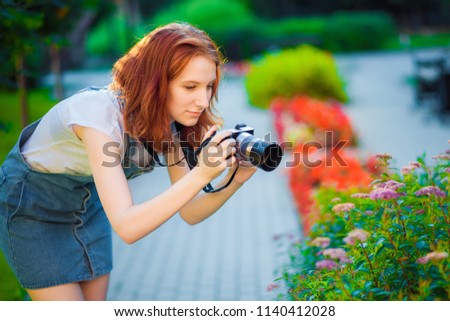Red-haired girl photographer taking pictures of flowers