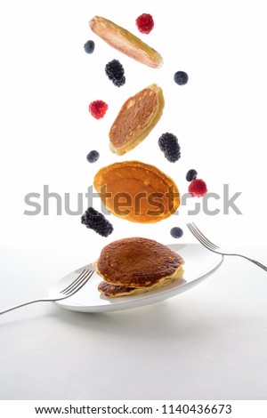 Flying stack of pancakes with blueberry, blackberry and raspberry isolated on white background Royalty-Free Stock Photo #1140436673