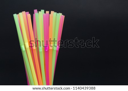 Closeup of bright colorful single use disposable plastic straw bunch as fun party vivid colored cocktail concept isolated on black background