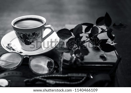 Vintage Book with reading glasses and cup of coffee with a rose flower on wooden surface.Concept of reading and gaining knowledge or close up of  a business man/women's working desk or space.