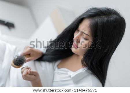 woman with a comb and problem hair loss sitting on bed at bedroom.