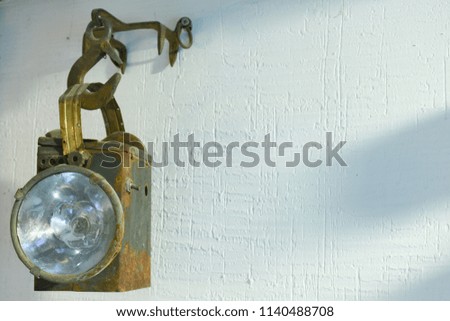 The old torch hangs on a white wall