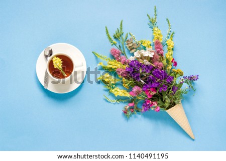 Field colorful rustic vintage flowers in waffle ice cream cone and cup of  herbs tea on blue turquoise background Concept Good morning  Summer Teatime Tea party Greeting card Flat Lay Copy space