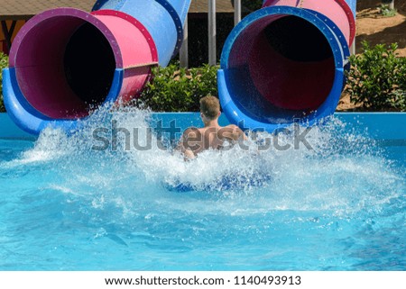 young man ride on a slide in a water park