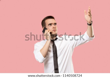 Bad news. Handsome businessman with mobile phone. The young business man standing isolated on pink studio background. Human emotions, facial expression concept.