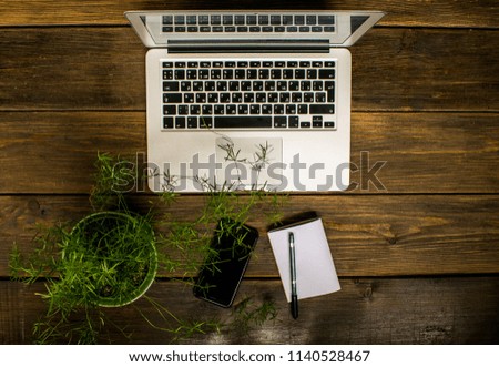 Top view of a business lay out - notebook, plant, phone and sheet of paper on stylish brown wooden background. Mock up composition for work and study. 