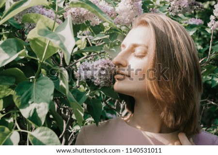 Lifestyle portrait of young white woman in lilac flowers and leaves, selective focus