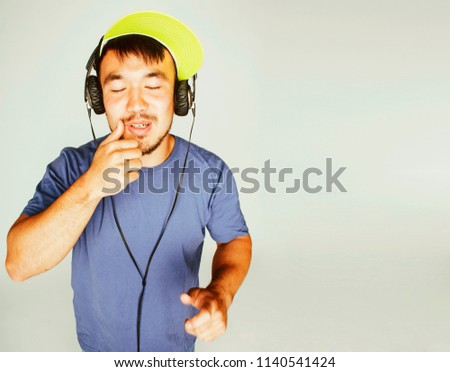 young asian man in hat and headphones listening music on white b