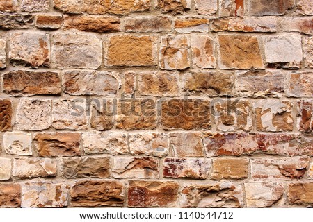 Wall texture of ancient old brick stone. Outdoor exterior castle facade with destroyed uneven pattern of shabby rock. Solid wall sandstone structure background. Grunge surface useful for 3d texturing 