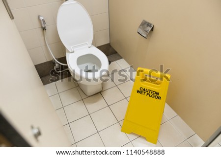 yellow caution sign in toilet. caution wet floor.flush toilet.