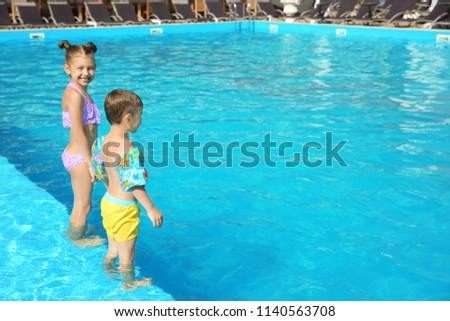 Little children standing in swimming pool on sunny day