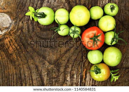 Green and red tomatoes on a wooden table stock photo