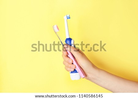 Woman holding manual and electric toothbrushes against color background Royalty-Free Stock Photo #1140586145