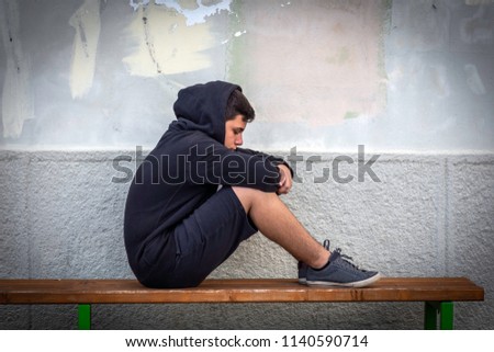 Little boy sad sitting alone at school hides his face Royalty-Free Stock Photo #1140590714