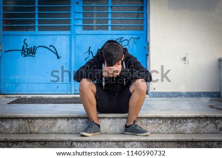 Little boy sad sitting alone at school hides his face Royalty-Free Stock Photo #1140590732