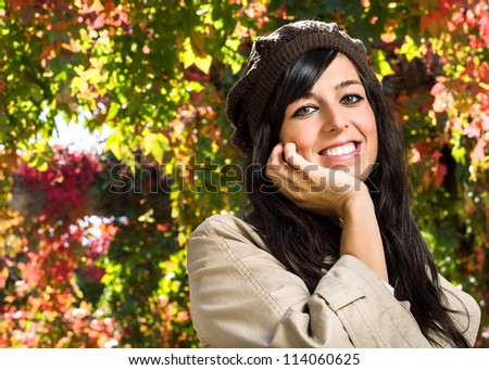 Cute and beautiful young brunette woman enjoys autumn on colorful leaves background