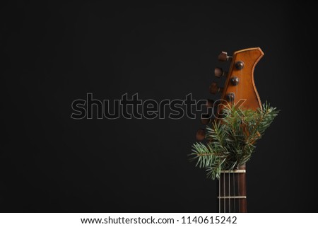Guitar with fir tree twig on black background. Christmas music concept