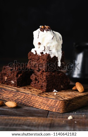 Chocolate brownies with vanilla ice cream on black background. Closeup view, selective focus