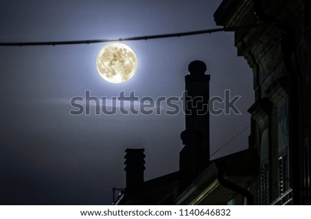 Full moon "hanging" between the roofs of the town