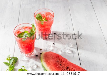 Watermelon drink in glass with a piece of watermelon and mint. Iced watermelon juice.