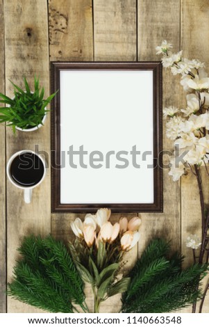 Wood picture frame and coffee with flower decoration on wood background. Rustic nostalgia flat lay.