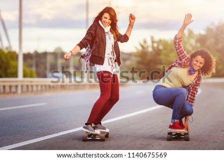 Skateboard girls riding long-boards down the road