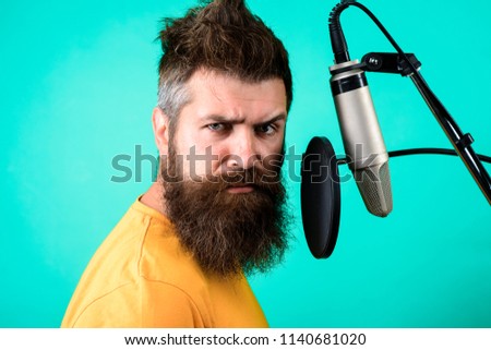 Brutal bearded singer with microphone on stage. Bearded man singing with microphone. Concert&music concept. Male lead vocalist singing in recording studio. Vocalist singing into condenser microphone.