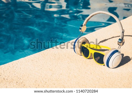 sunglasses in headphones listen to music near the pool, a fun picture of a tropical vacation