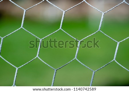 White football net with blurred green grass field background.