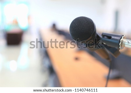 Close-up of black microphone in meeting room there is a conference table in the background selective focus and shallow depth of field