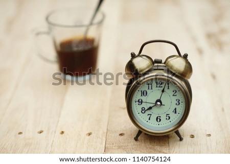 Analog alarm clock on wooden table with blur green garden background, 8 am., 8 o'clock, copy space
