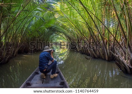 Photographers on boat and Rows of Nipa palm (Nypa fruticans Wurmb) in Khlong Bang Bai Mai which itself is part of the Tapi River, the longest river in the southern region of Thailand : Surat Thani