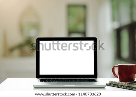 Workspace wood desk with Laptop with blank screen,Interior home blurred background at light bokeh.
