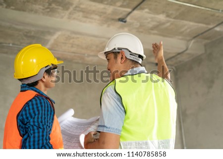 Civil engineer or architect and worker with safety helmet checking building ,engineering and architecture concept.Blue print is fake only for stock photo.