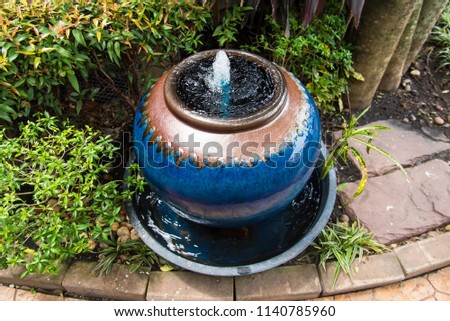 Jar fountain decoration in the green garden.Thailand